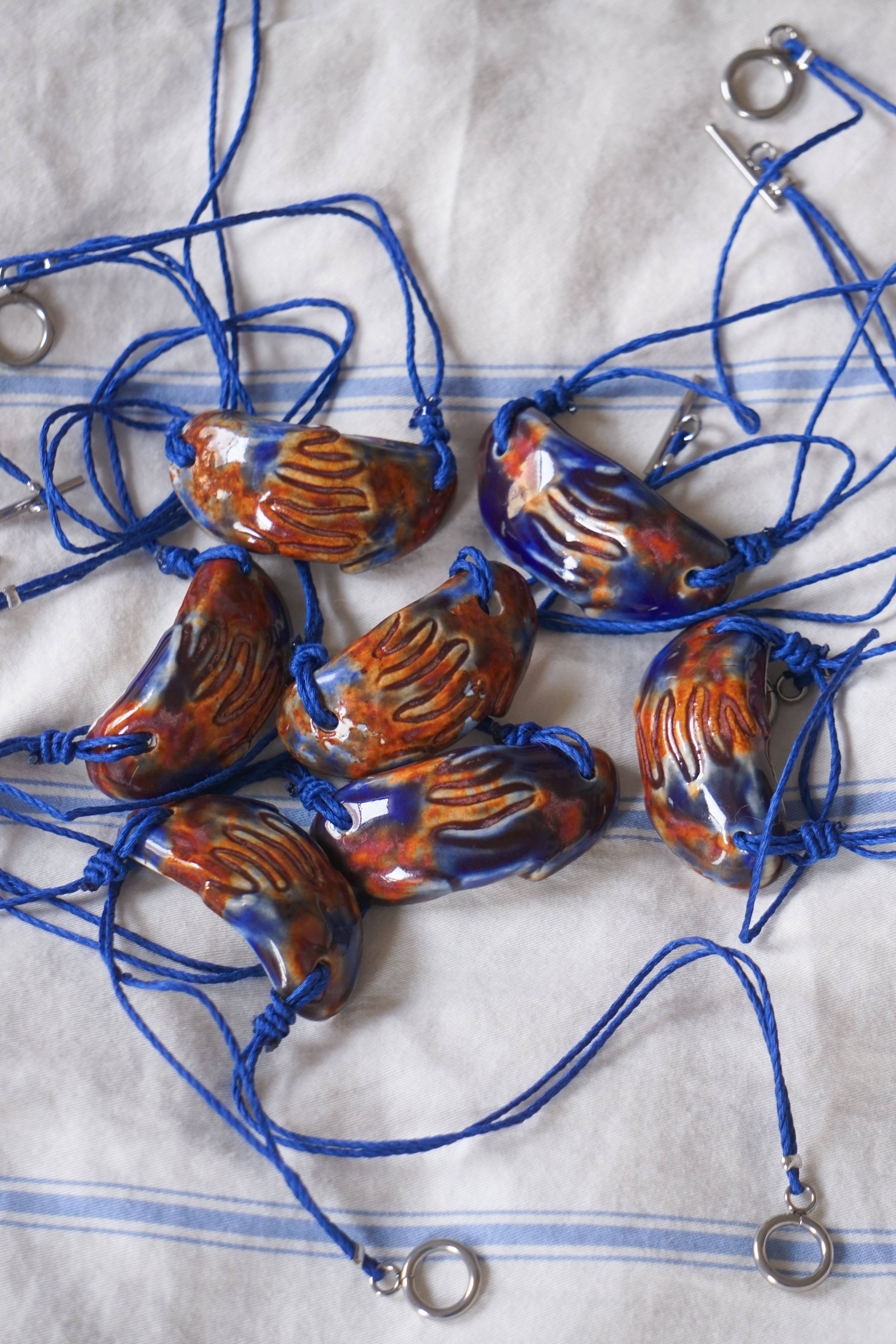 Decorative necklaces with ceramic beads on a textured fabric background