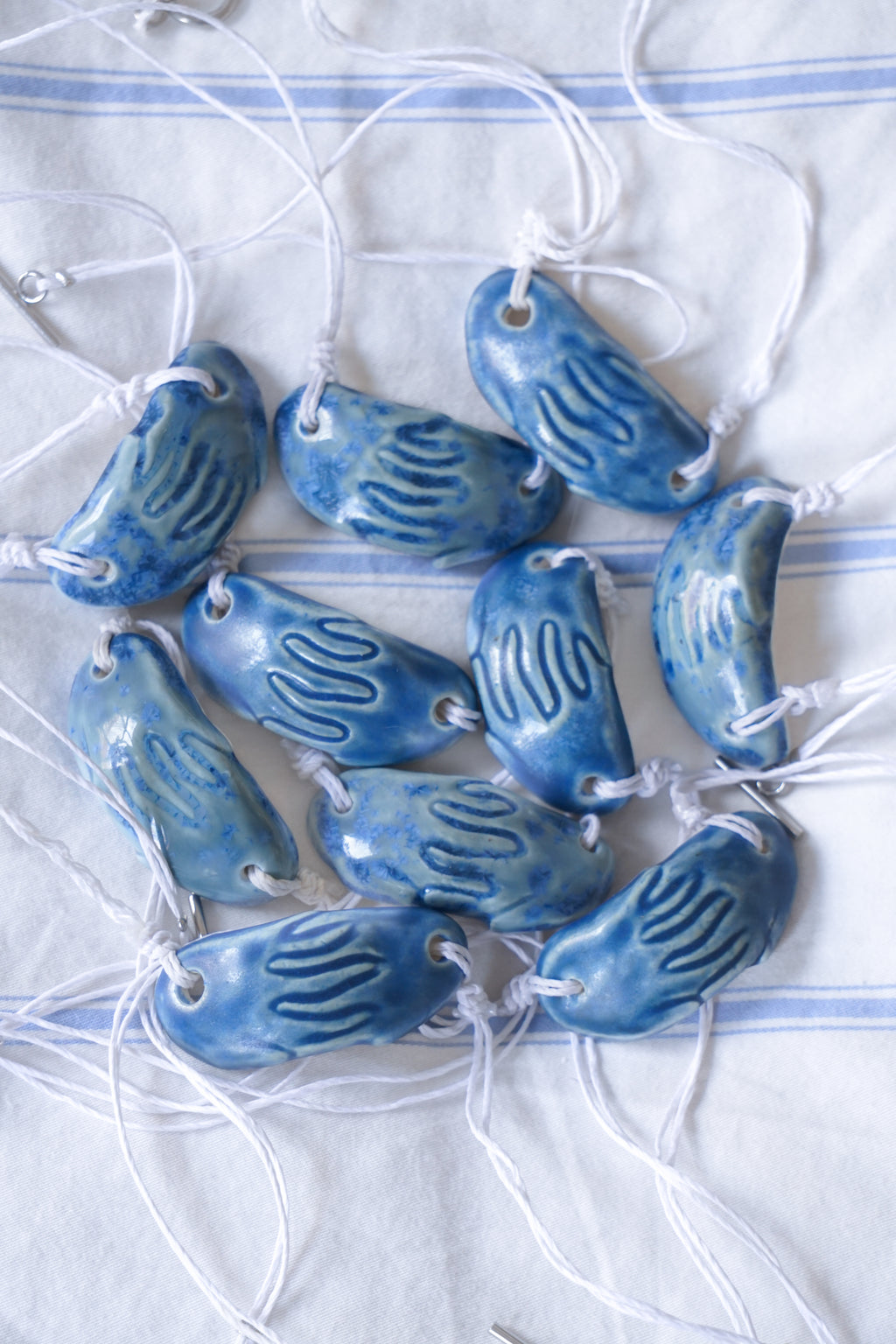 Blue ceramic pendants on white strings against a white background