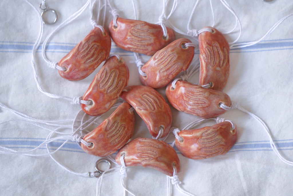 Handmade coral ceramic beads on a white and blue striped fabric background