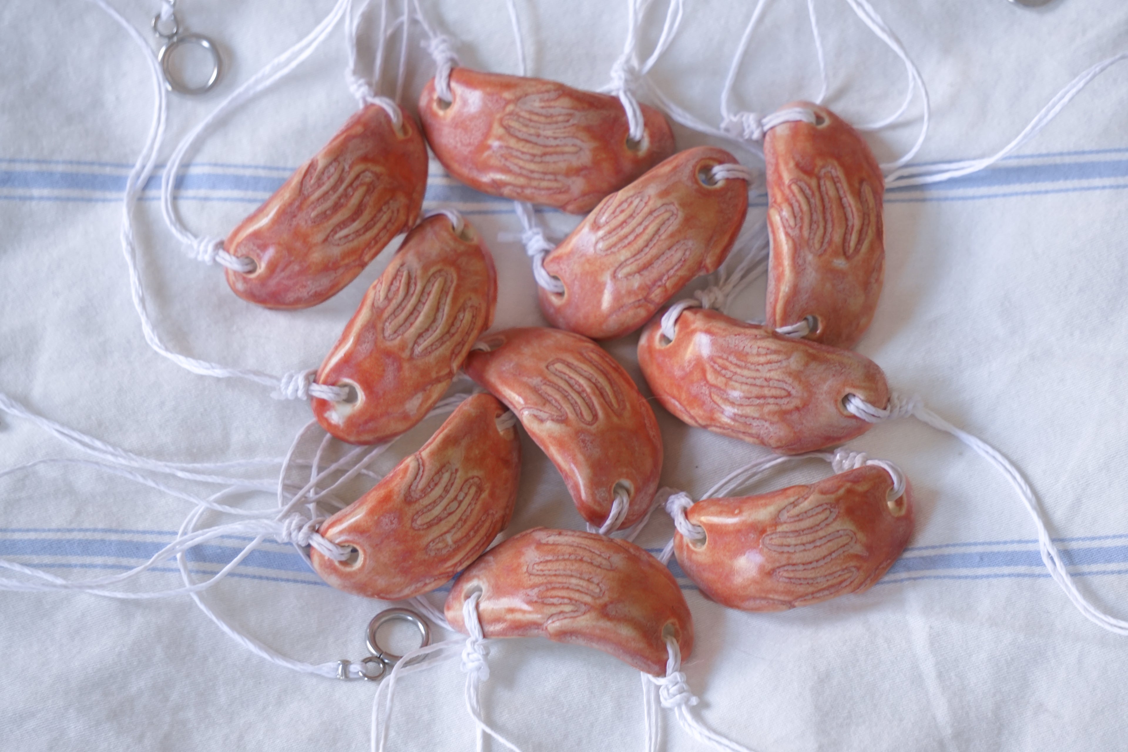 Handmade coral ceramic beads on a white and blue striped fabric background