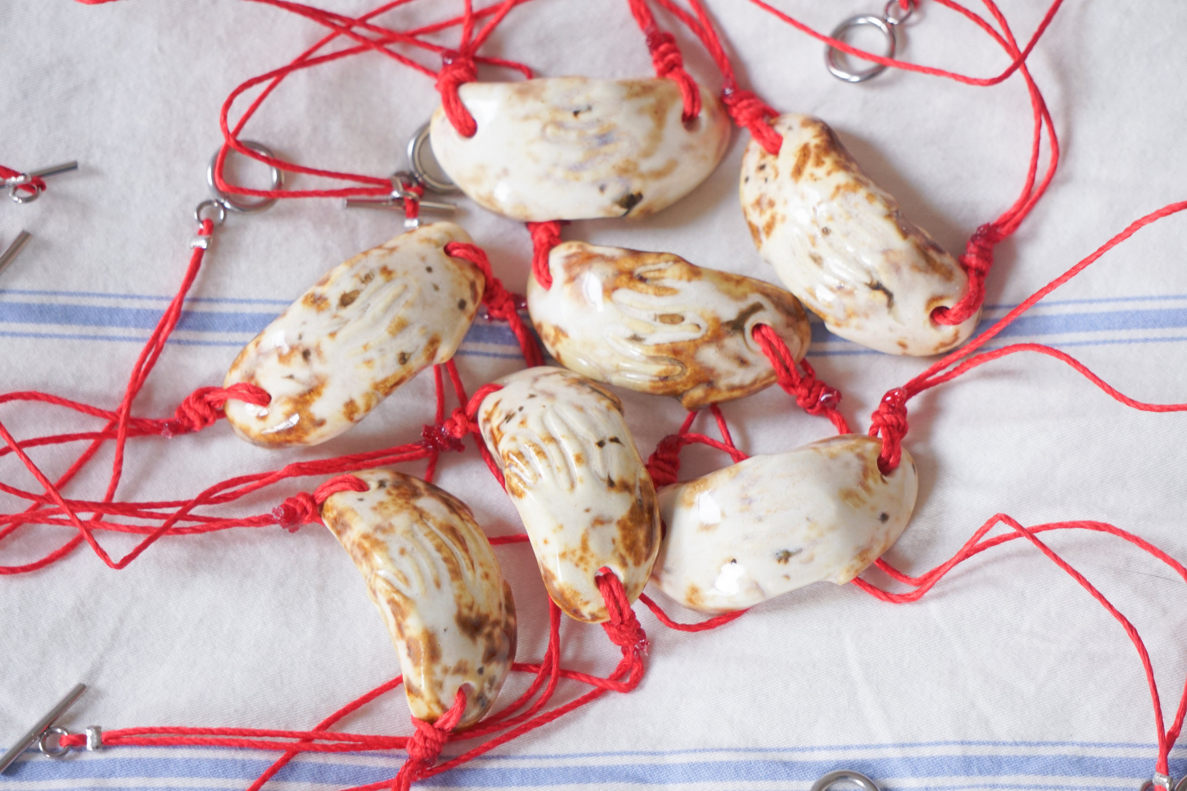 cow print ceramic necklaces with red cord against a white fabric background.