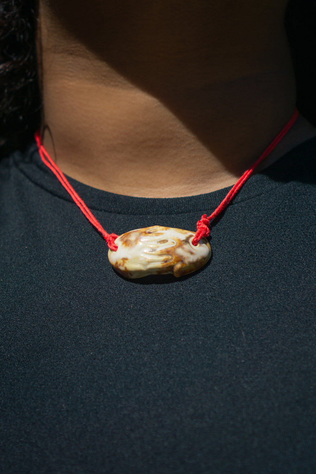 cow print ceramic necklace with a red cord and a pendant replicating holding hands. Princess style necklace.