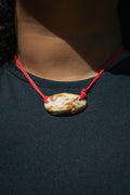 cow print ceramic necklace with a red cord and a pendant replicating holding hands. Princess style necklace.